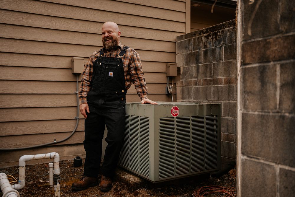 Levi, owner of Fix It First Heating & Cooling, beside a Rheem AC unit